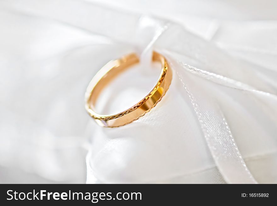 Classic gold wedding ring on white satiny fabric. Classic gold wedding ring on white satiny fabric