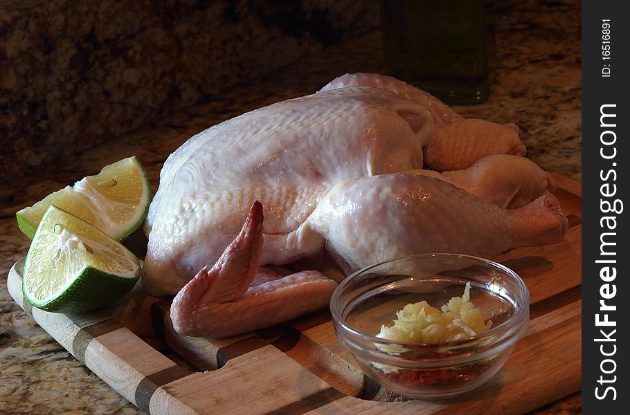 A fresh organic chicken with lemon on wooden board. Natural light from the kitchen window.