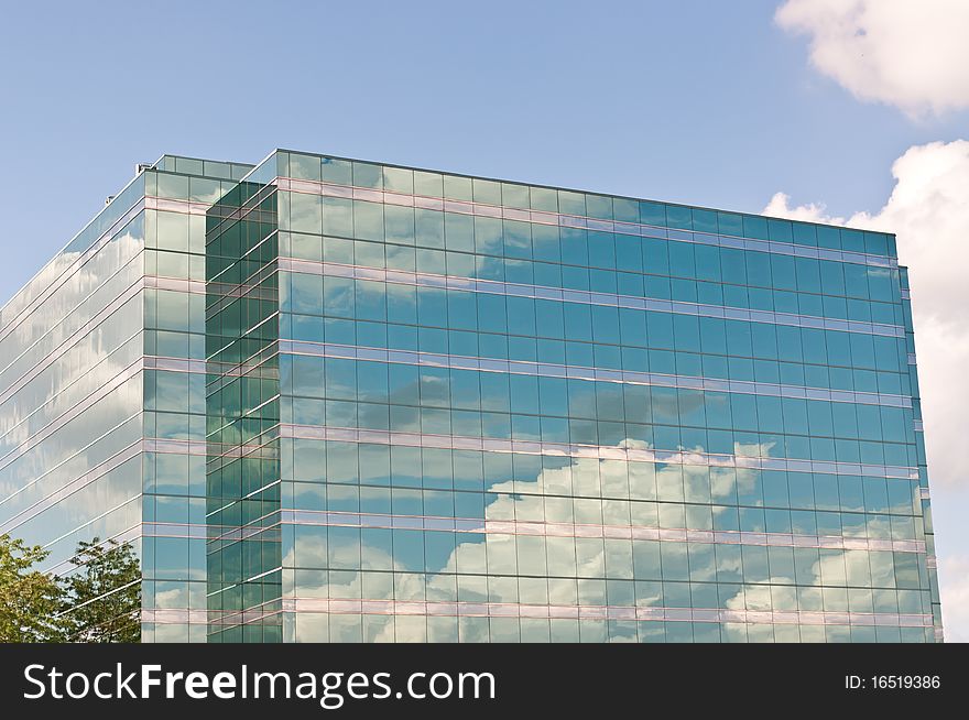 Sky and clouds are reflected in the mirrored windows of this modern office building. Sky and clouds are reflected in the mirrored windows of this modern office building.