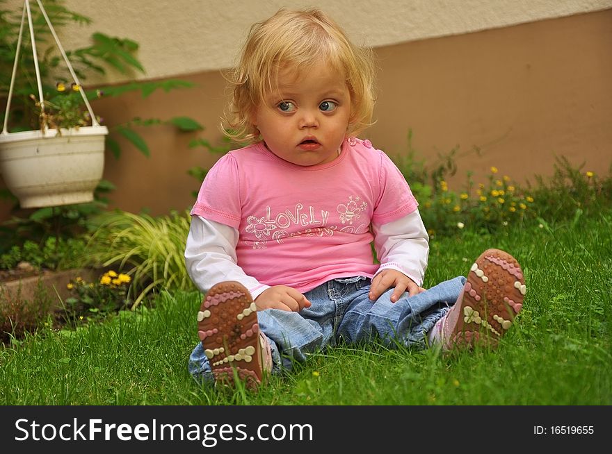 Child girl sitting on the green grass. Child girl sitting on the green grass