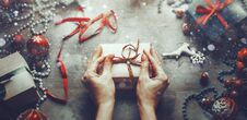 Christmas New Year Concept Top View. Unrecognizable Woman Wrapping Draws A Gift Box On Wooden Table With Snow And Bokeh, Point Of Stock Image