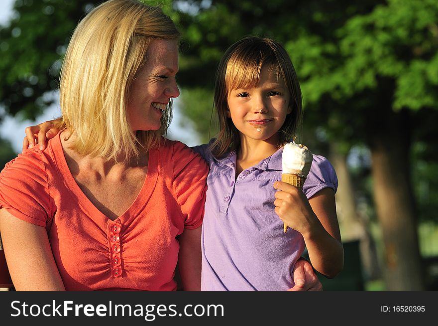 Loving mother watching her little girl eating ice cream. Loving mother watching her little girl eating ice cream