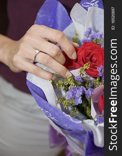 A woman receiving diamond ring and rose bouquet