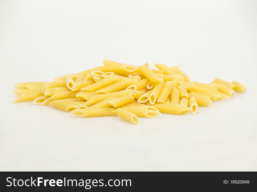 Scattered yellow pasta in the shape of a cylinder on the white backgrand