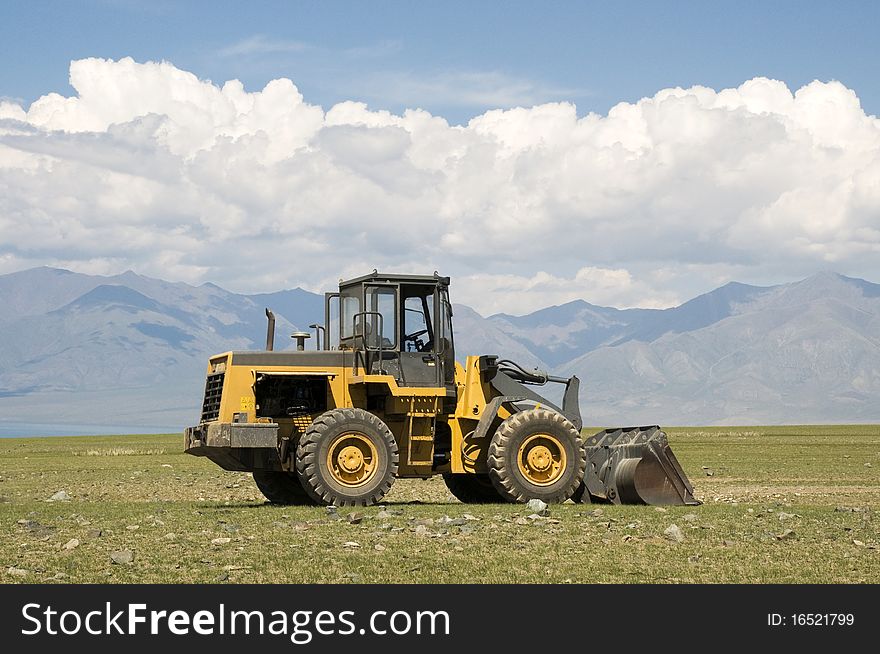 Tractor in the steepe with the mountains in the background. Tractor in the steepe with the mountains in the background