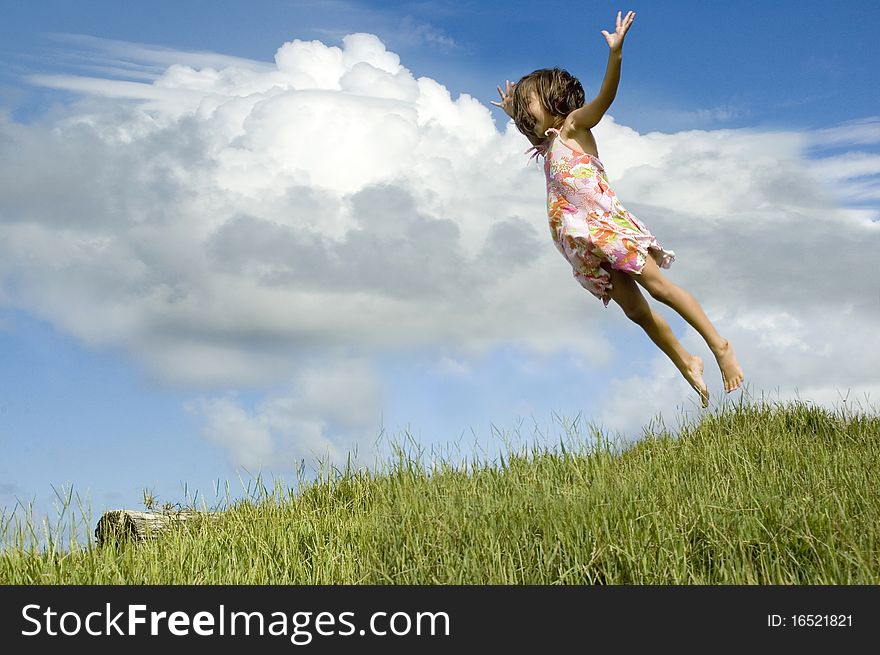 Little girl jumping high in the air, grass and sky