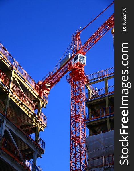 Image of a crane working on construction of a building under the blue sky. Image of a crane working on construction of a building under the blue sky