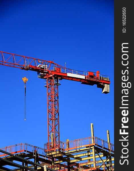 Image of a crane working on construction of a building under the blue sky