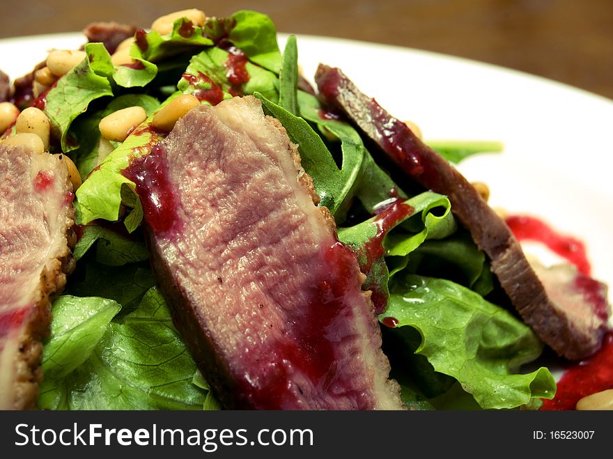 Meat with salad and nuts served on the white plate. Meat with salad and nuts served on the white plate