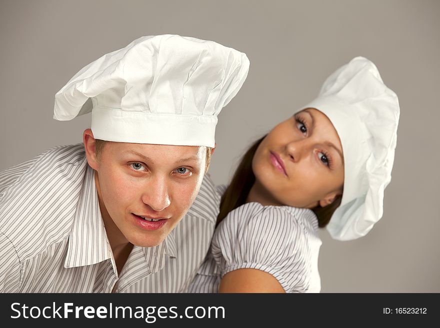 Young loving couple cooks. Over gray background