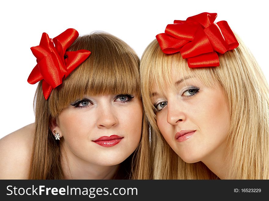 Portrait of two smiling young women with gift red bow over white background