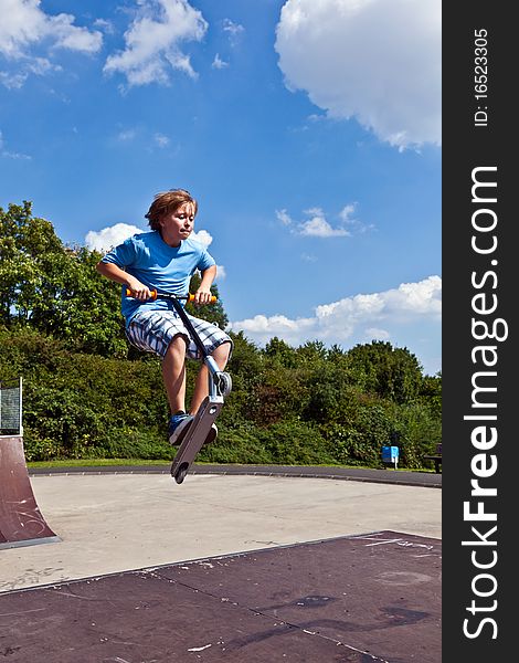 Young boy going airborne with his scooter at the skate park