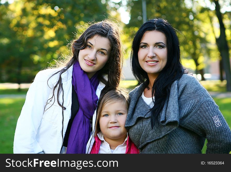 Young family taking healthy stroll through autumn park and have fun