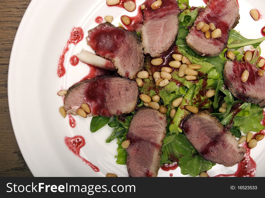 Meat with salad and nuts served on the white round plate. Meat with salad and nuts served on the white round plate