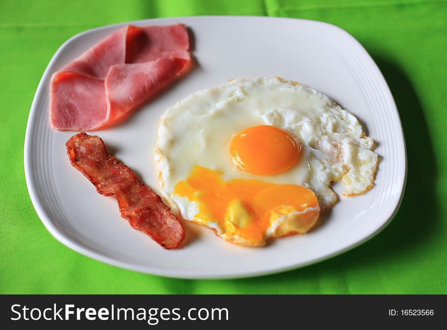 A high-calorie breakfast of fried egg, sausages, close-up in a non-stick pan.