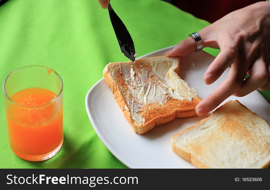 Knife spreading butter on toast in white plate. Knife spreading butter on toast in white plate