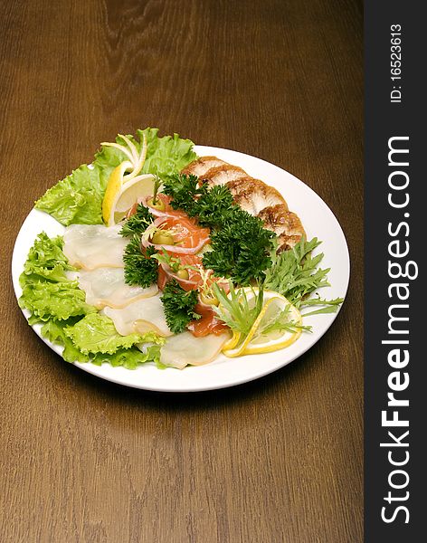 Appetizer made of meat and fish served with salad on the round plate