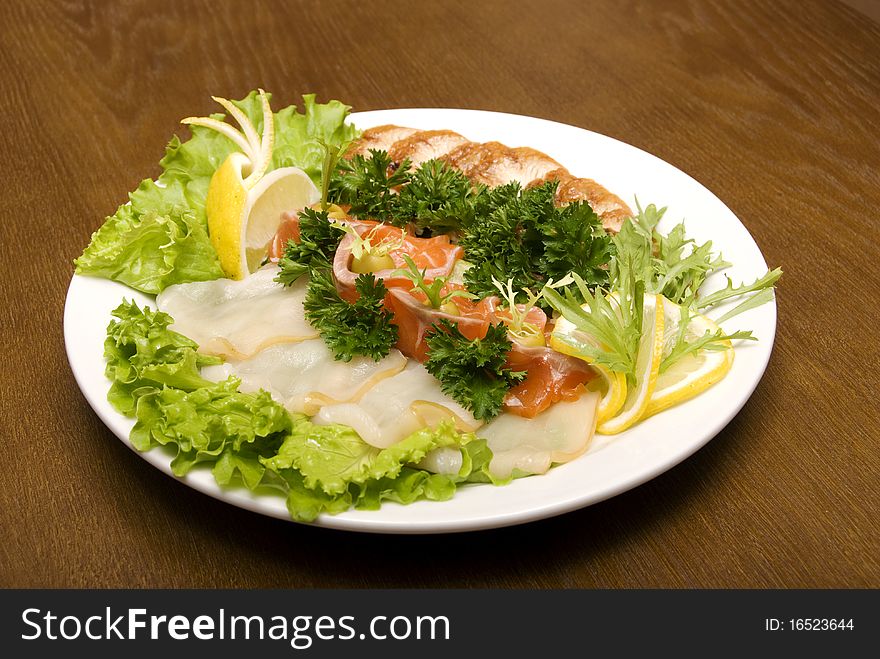 Appetizer made of meat and fish served with salad on the round plate