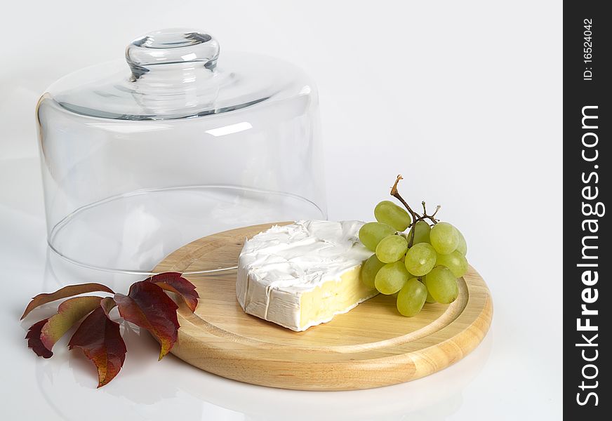 The photo shows a cheese cover and a vine leaf over white