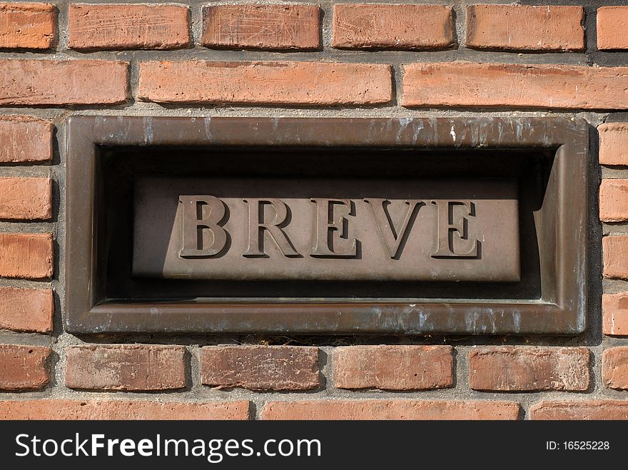 Danish letterbox in a solid brickwall with the word BREVE. In english LETTER.