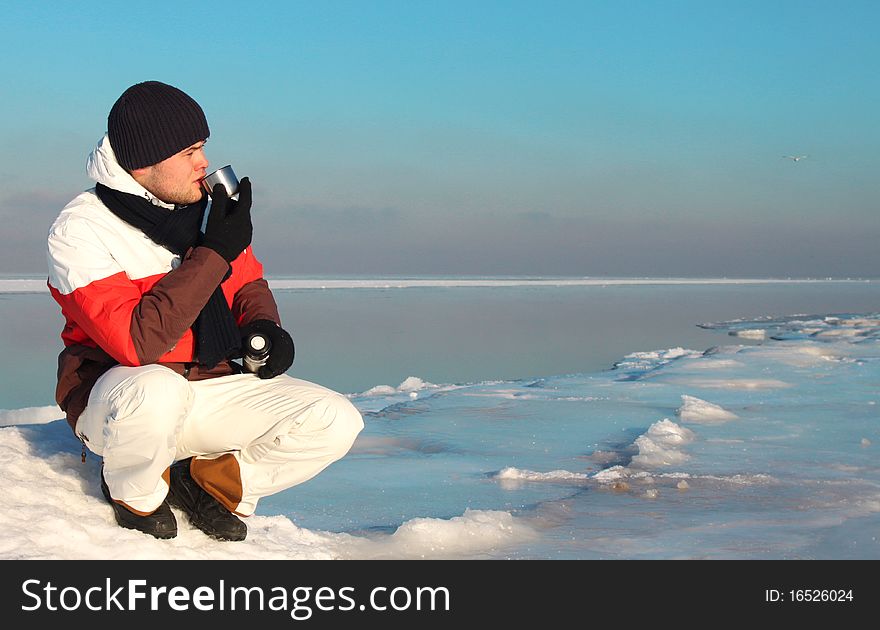 Young handsome man drinks hot tea/coffee in Nothern Pole