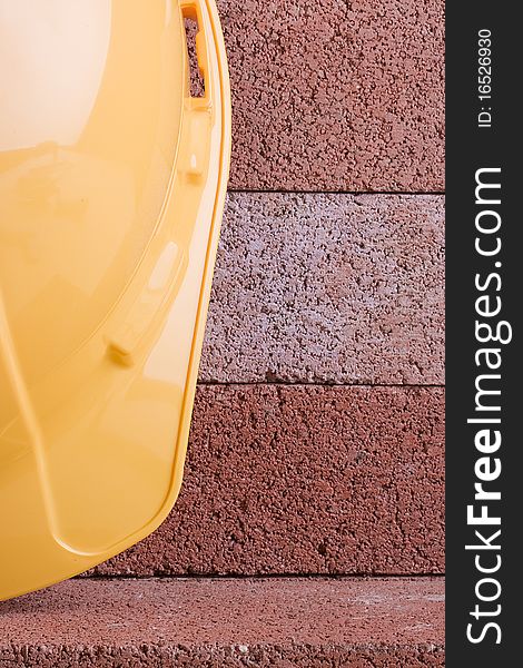 Yellow hard hat on a background of red bricks.