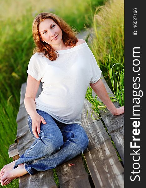 Portrait of beautiful happy pregnant woman on meadow