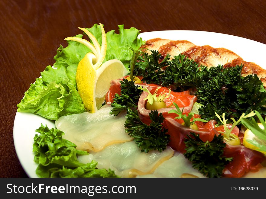 Appetizer made of meat and fish served with salad on the round plate