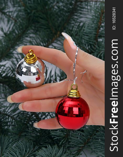 Female hand holding a Christmas ball on fur-tree natural background. Female hand holding a Christmas ball on fur-tree natural background