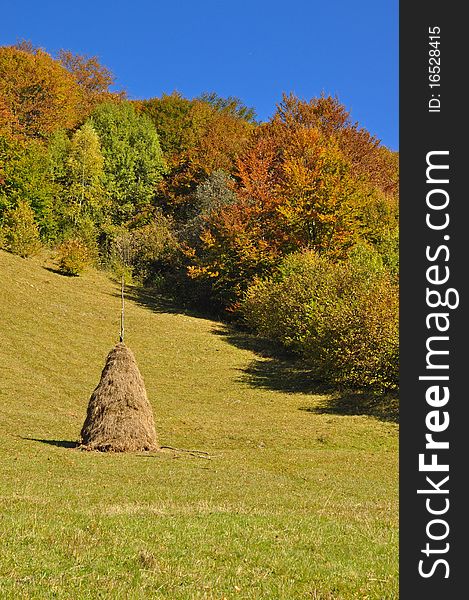 A haystack on an autumn hillside in a landscape under the dark blue sky.