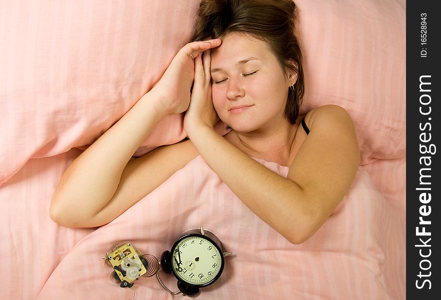 Adorable sleeping woman with broken alarm-clock