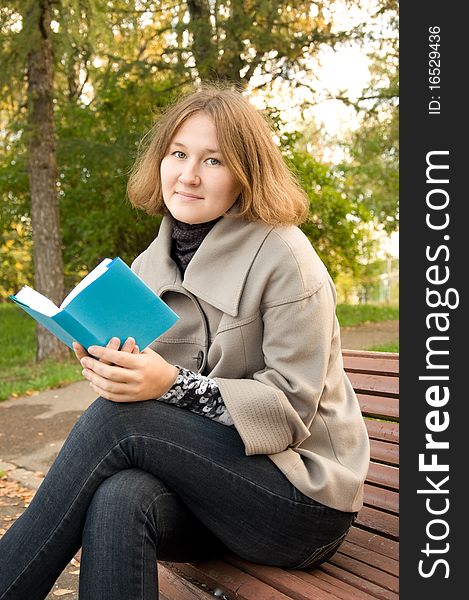 Adorable woman is sitting on the bench and reading a book. Adorable woman is sitting on the bench and reading a book
