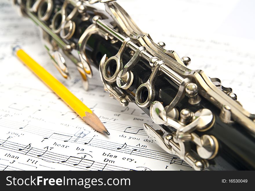 Close-up of clarinet on music sheet with the white background
