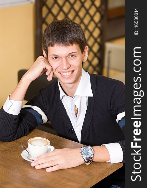 Young man with cup of coffee in cafe