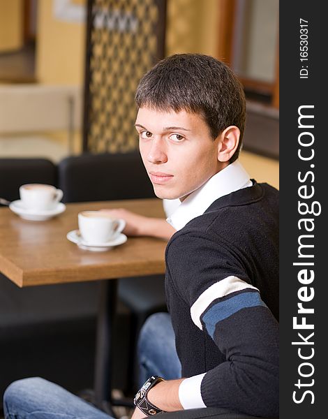 Young man with cup of coffee in cafe