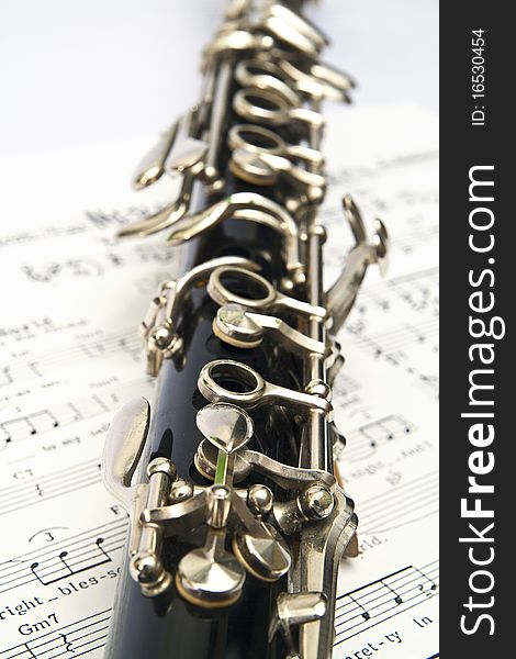 Close-up of clarinet on music sheet with the white background