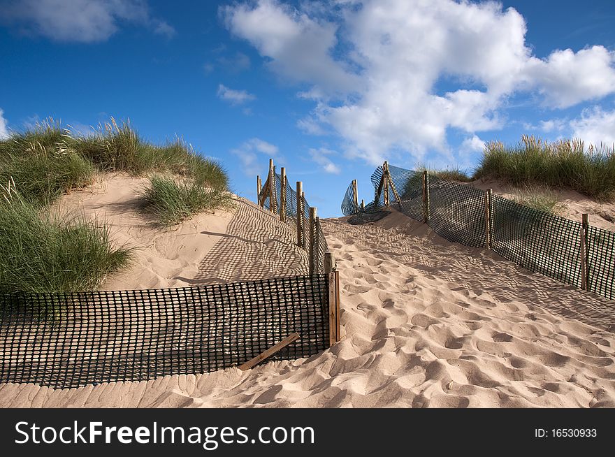 Path through sand dunes. dunes fenced off for protection from erosion. Path through sand dunes. dunes fenced off for protection from erosion