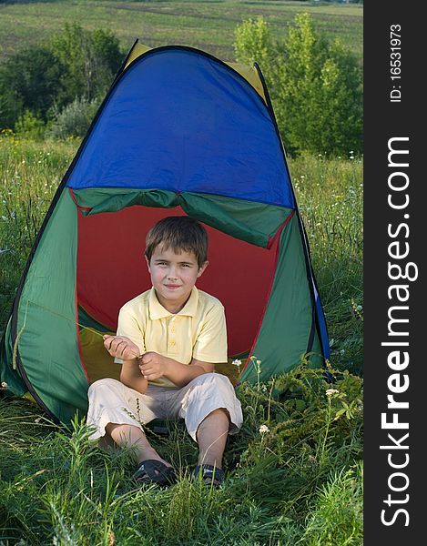 Boy in camping tent in summer forest