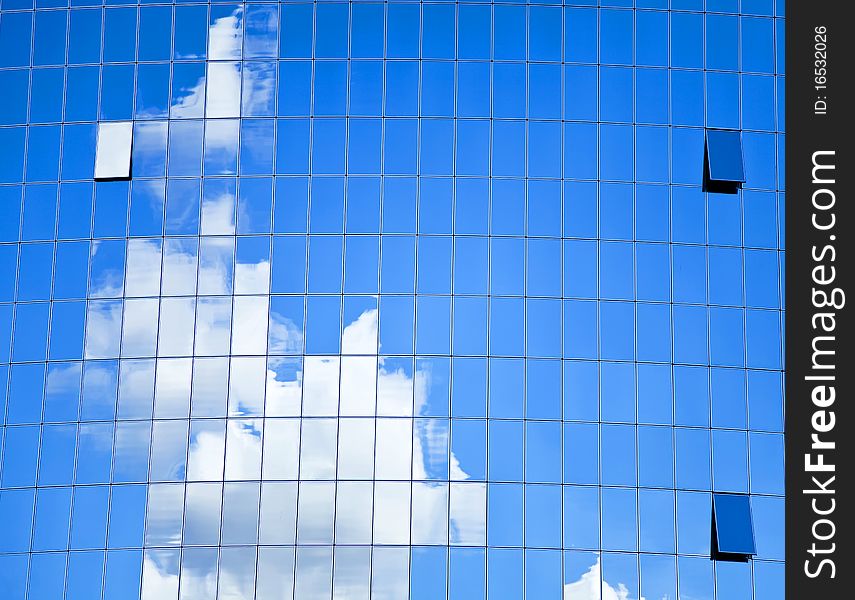 Highrise glass building with sky and clouds reflection.