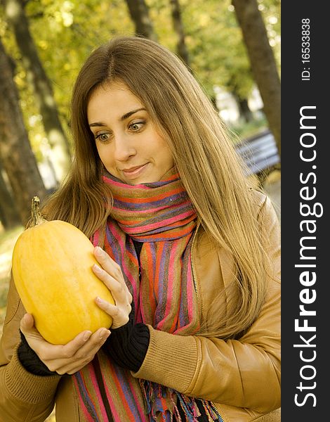 Smiling girl holding a pumpkin. Autumn on the street