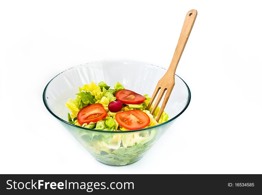 A bowl of fresh green salad decorated with tomato and wooden spoon. A bowl of fresh green salad decorated with tomato and wooden spoon