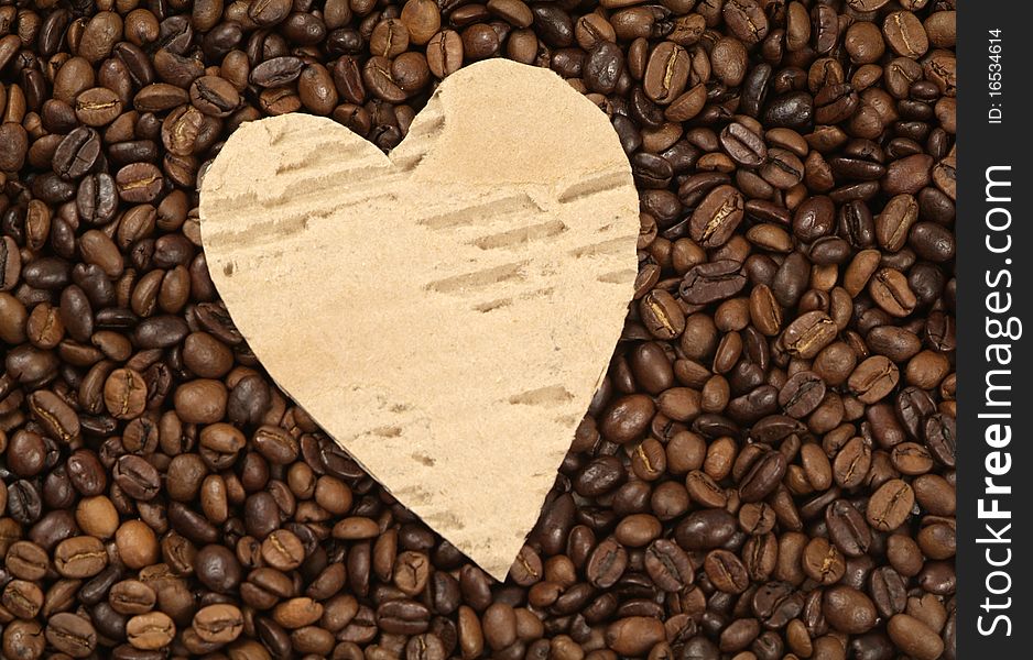 Coffee beans with heart shaped piece of cardboard in the middle. Coffee beans with heart shaped piece of cardboard in the middle