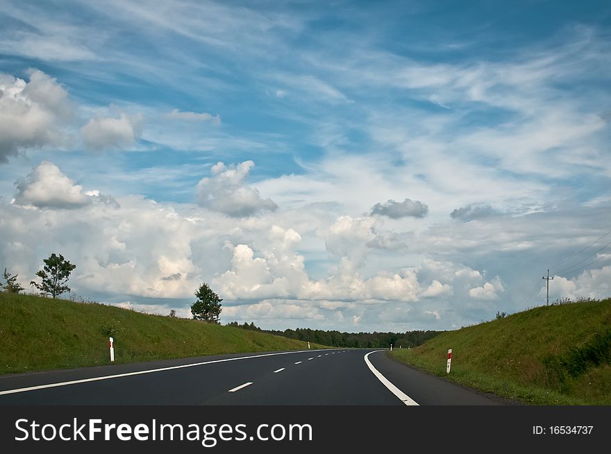 Traveling on empty asphalt road in countryside under interesting cloudy sky