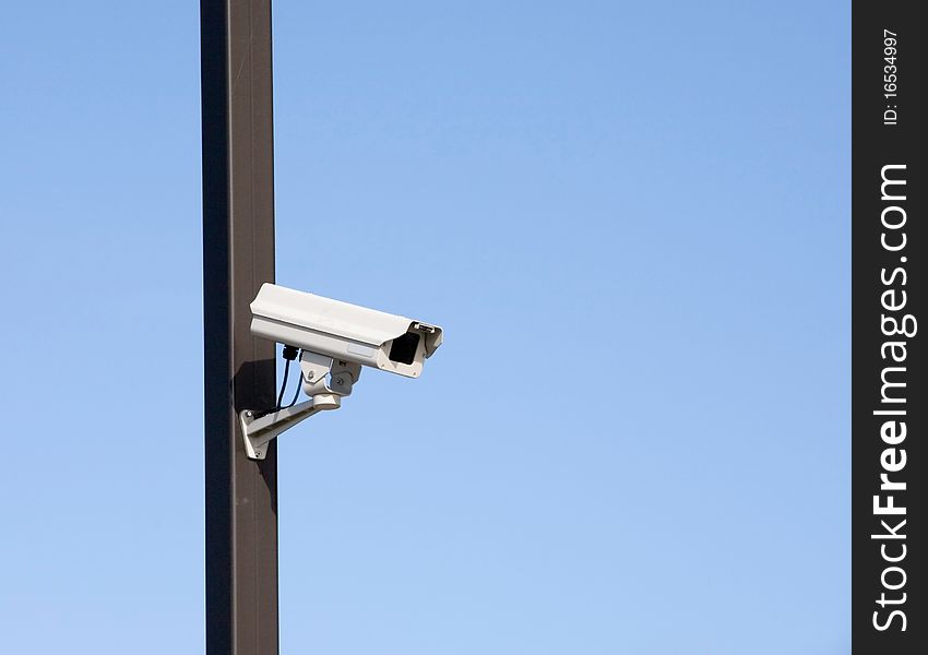 Surveillance camera on light pole in parking lot. Surveillance camera on light pole in parking lot