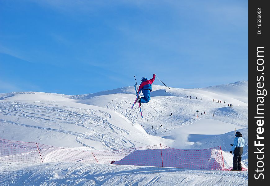 Young skier in blue performing a tele-heli jump