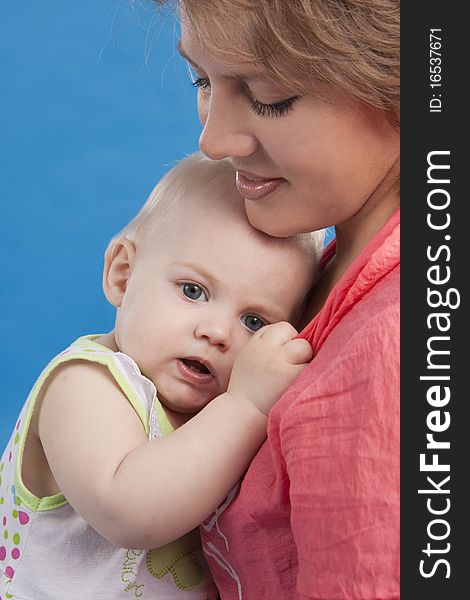 Young and beautiful mother with her sweet little daughter isolated on blue. Young and beautiful mother with her sweet little daughter isolated on blue.