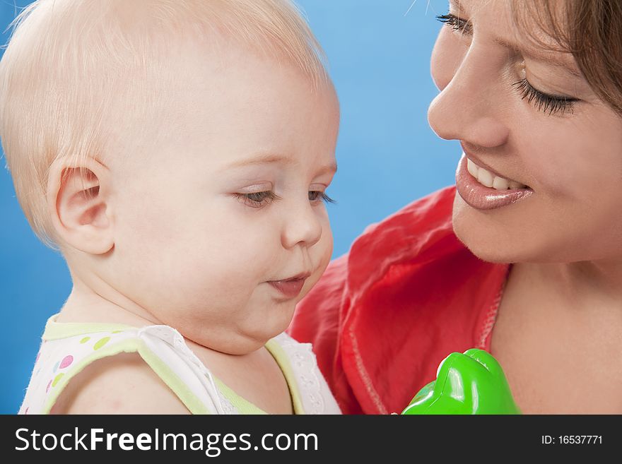 Young and beautiful mother with her sweet little daughter isolated on blue. Young and beautiful mother with her sweet little daughter isolated on blue.