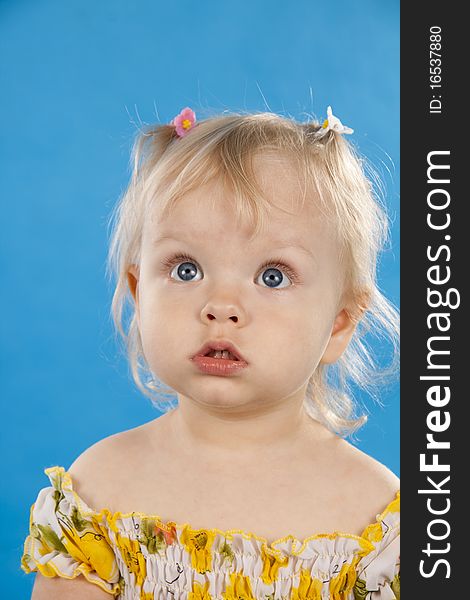 Beautiful little girl the blonde on a blue background. Beautiful little girl the blonde on a blue background