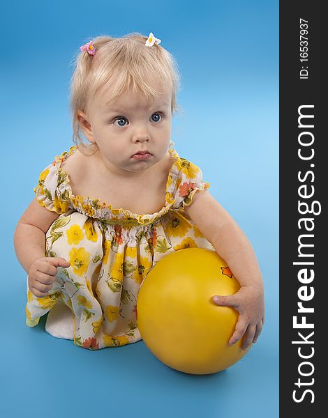 Little girl plays with yellow ball. Blue background. Little girl plays with yellow ball. Blue background.
