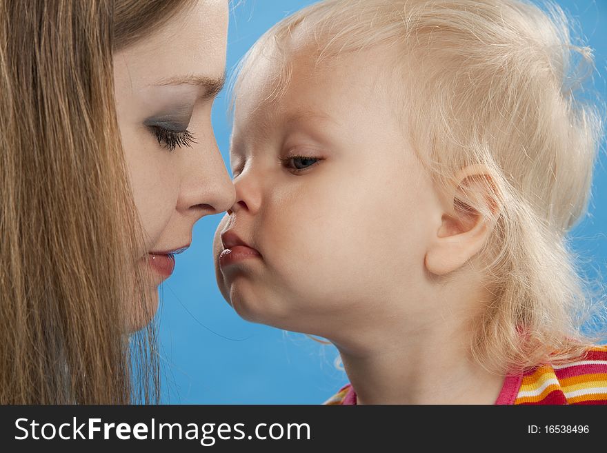 Young and beautiful mother with her sweet little daughter isolated on blue. Young and beautiful mother with her sweet little daughter isolated on blue.